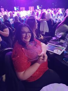 Clare holding her award at the Great British Care Awards, smiling proudly.